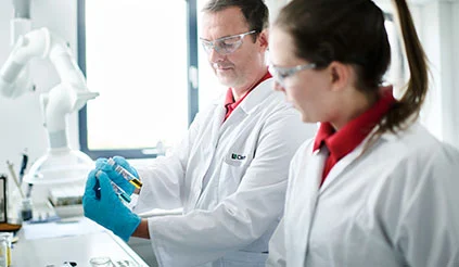 Zwei Mitarbeiter von REMONDIS (ein Mann und eine Frau) bei der Analyse von Abfallproben in einem Labor.